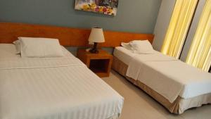 a bedroom with two beds and a lamp on a table at 21 Lodge in Nusa Dua