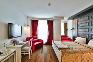 イスタンブールにあるSenatus Hotel - Special Classのベッド、デスク、赤い椅子が備わるホテルルームです。