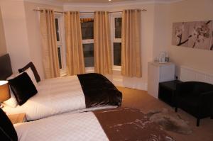 a bedroom with a bed and a chair and windows at Sapphire Hotel London in London