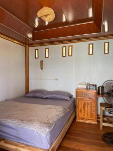 a bedroom with a bed and a table and a fan at Kertasari Golden House Homestay in Pulau Sarang