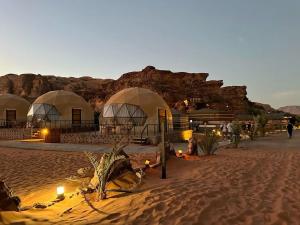 a beach with domes and people sitting on the sand at Wildlife Camp in Disah