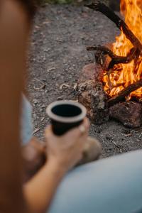 una persona sosteniendo una taza frente al fuego en Secluded & Pet Friendly Cabin Deep in Nature - Cybele, en Coleyville