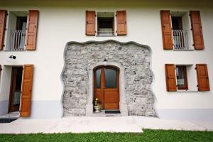 - un bâtiment blanc avec une porte et des fenêtres dans l'établissement Albergo Diffuso Tolmezzo, à Tolmezzo