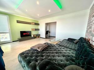 a living room with a large couch in front of a tv at Apartman Aniko in Dunajská Streda