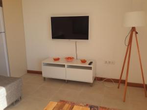 a room with a tv on a wall with a table at Kasinn Apart Turuncu in Kaş