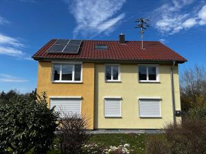 a yellow house with solar panels on the roof at Ferienwohnung im Heiligenberg in Langenburg +3 photos