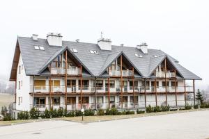 ein großes weißes Gebäude mit schwarzem Dach in der Unterkunft Viva Maria Residence in Zakopane