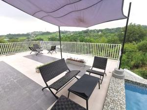 a patio with chairs and an umbrella and a pool at Overlooking & Serene Resthouse wt Pool in Antipolo in Antipolo