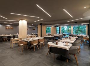 a dining room with tables and chairs and windows at Parkhotel Fedora in Campitello di Fassa