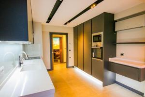 a kitchen with black cabinets and white counter tops at Utopia Suite in Burunabat