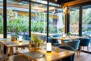 a restaurant with tables and chairs and large windows at Wyndham Garden Naithon Phuket in Nai Thon Beach