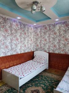 a bed in a room with flowers on the wall at Nice Hostel in Sary-Mogul +3 photos