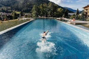 a man in a swimming pool in the water at Thermenwelt Hotel Pulverer in Bad Kleinkirchheim