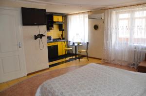 a bedroom with a bed and a kitchen with yellow cabinets at Apartment on Ingenernaya 17 in Mykolaiv