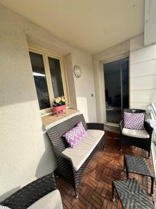 a balcony with a wicker chair and a bench with a pillow at L Elegant Cozy Plein Centre in Saint-Avertin