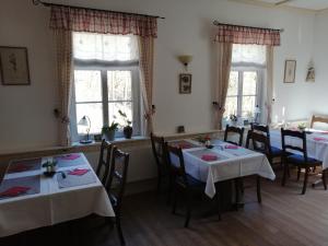 a dining room with tables and chairs and windows at Gasthaus Pension Bretthäusl in Glashütte