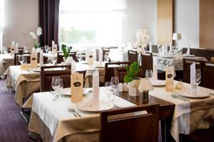 uma sala de jantar com mesas e cadeiras com toalhas de mesa brancas em Grand Hotel Primus - Terme Ptuj - Sava Hotels & Resorts em Ptuj