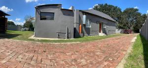 a house on a brick road next to a building at Relax Guest House in Ermelo