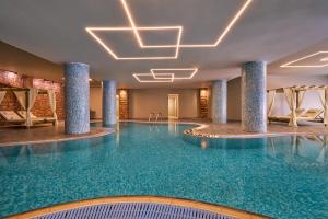 a swimming pool in a hotel with columns and chairs at Lindos Imperial Resort & Spa in Kiotari