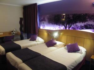 Habitación de hotel con 2 camas con almohadas moradas en Kyriad Direct Arles, en Arles