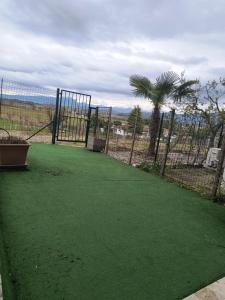 a fence with a green field with a palm tree at B&B Il Tramonto in Pastrengo