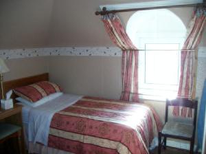 niewielka sypialnia z łóżkiem i oknem w obiekcie The Ivy House Ferry Link w mieście Stranraer