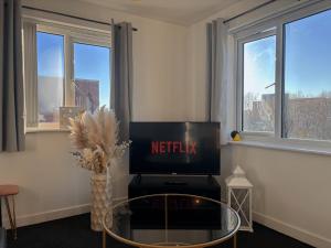 a living room with a tv and a glass table at Apollo Apartment in Coventry