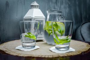 two glasses of water and a bottle with a plant in it at Hotel House in Rishon LeẔiyyon