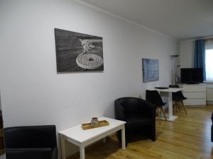 een woonkamer met stoelen en een tafel en een foto bij Fewo-Seetank in Friedrichskoog