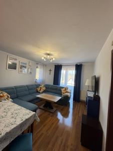 Una sala de estar con un sofá azul y una mesa. en Apartament Błękitny, en Krynica Morska