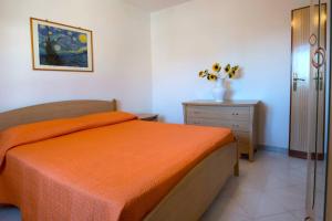 a bedroom with a bed with an orange bedspread and a dresser at Appartamento Milano Vista Mare by Salento Prime in Torre Vado