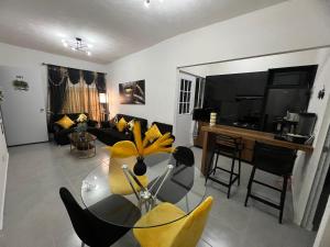 a living room with a glass table and yellow chairs at Cristal diamante in Los Algodones