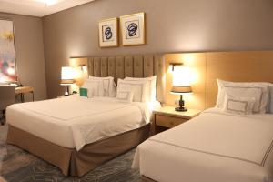 a hotel room with two beds and two lamps at Grand Cosmopolitan Hotel in Dubai