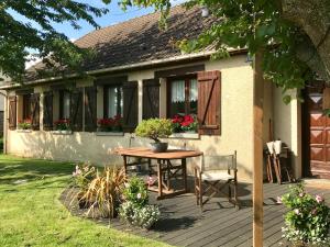una casa con un tavolo e una sedia su un ponte di Chambres tout confort du Tilleul a Bosc-Bénard-Commin