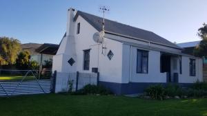 a small white church with a fence in the yard at Opstal Herberg in Bredasdorp