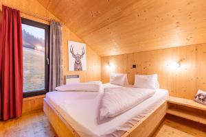 a bed in a wooden room with a window at Almdorf Hohentauern by ALPS RESORTS in Hohentauern