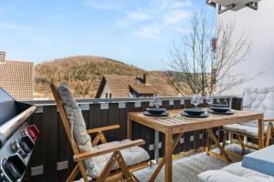 a patio with a wooden table and chairs on a balcony at JUNEs - NEU mit Balkon, Grill, PS5, Bikekeller in Bad Berleburg