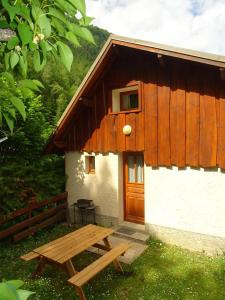 un edificio con puerta de madera y mesa de picnic en Les Oulles 10, en La Chapelle-en-Valgodemard