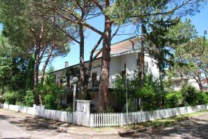 a white fence in front of a house with trees at Villa Lucilla in Grado