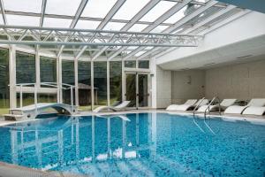 a swimming pool with white chairs and a glass ceiling at Golf Hotel in Folgaria
