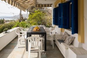 una mesa y sillas en un balcón con persianas azules en Villa Panorama in Pefkos, en Pefki