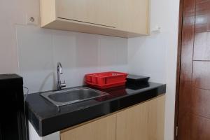 eine Küche mit einem Waschbecken und einem roten Tablett auf der Theke in der Unterkunft Cozy and Strategic 2BR Apartment at Gateway Pasteur By Travelio in Bandung