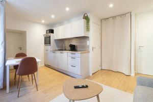 a kitchen with white cabinets and a table and chairs at Ile Bailleron - T2 - centre-ville in Vannes +8 photos