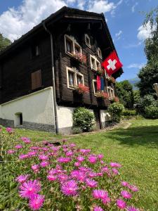ein Haus mit einer Flagge und Blumen im Hof in der Unterkunft Chalet Piumogna in Faido