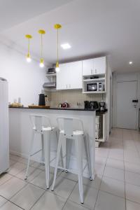 ニテロイにあるSurpreenda-se em Camboinhas! Piscina e Confortoの白いキャビネットと白いスツール付きの白いキッチン +39枚の写真