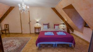 Un dormitorio con una cama con sábanas moradas y una lámpara de araña. en Gîte Le Grand Albizia, en Cellettes 42 fotos más