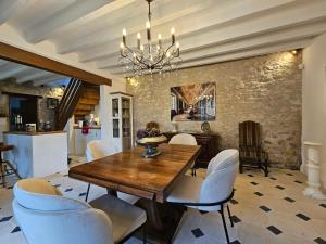a dining room with a wooden table and white chairs at Maisons du Cerf et du Tilleul in Châtillon-sur-Cher