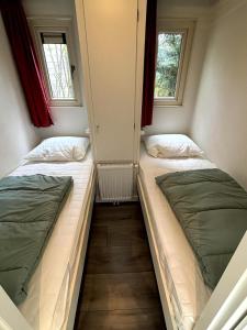 two beds in a small room with two windows at Fijn Boschalet Midden op de Veluwe, 2 fietsen in Hoenderloo +7 photos