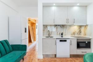 a kitchen with white cabinets and a green couch at Cabanas de Tavira - T1 in Cabanas de Tavira