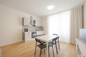 a white kitchen with a table and chairs at Wave Island A15 in Lido di Jesolo